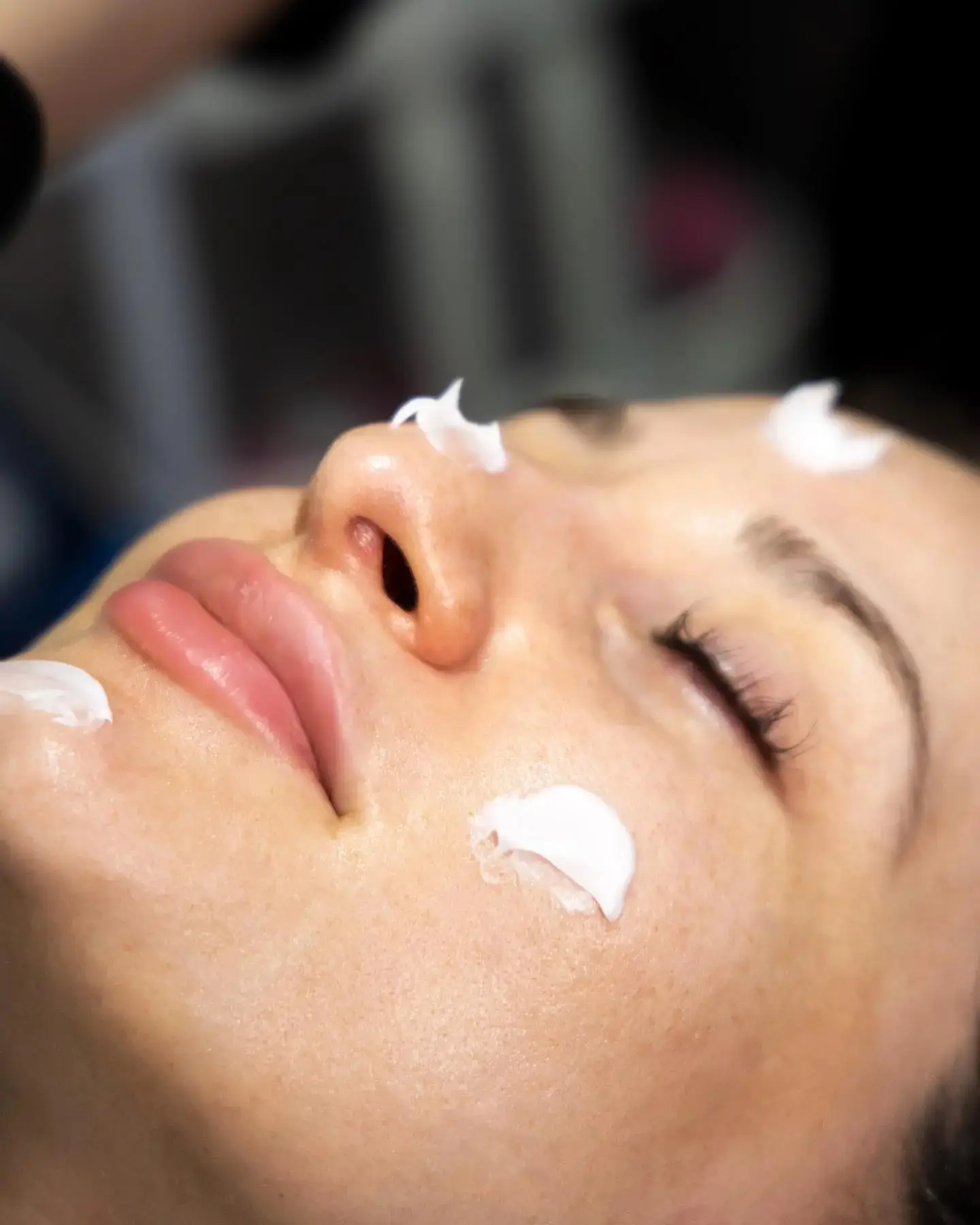 Nærbillede af kunde med lukkede øjne og creme på næse og kind under en peeling